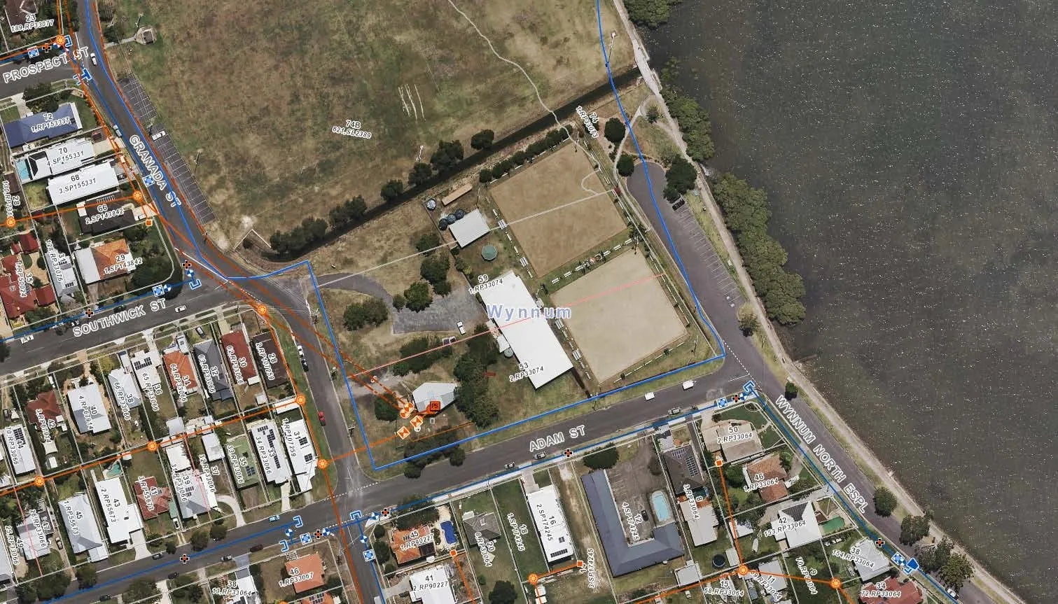 An aerial survey map of the Wynnum site on Adam Street, with property boundaries and service lines marked, and Moreton Bay along the eastern edge.