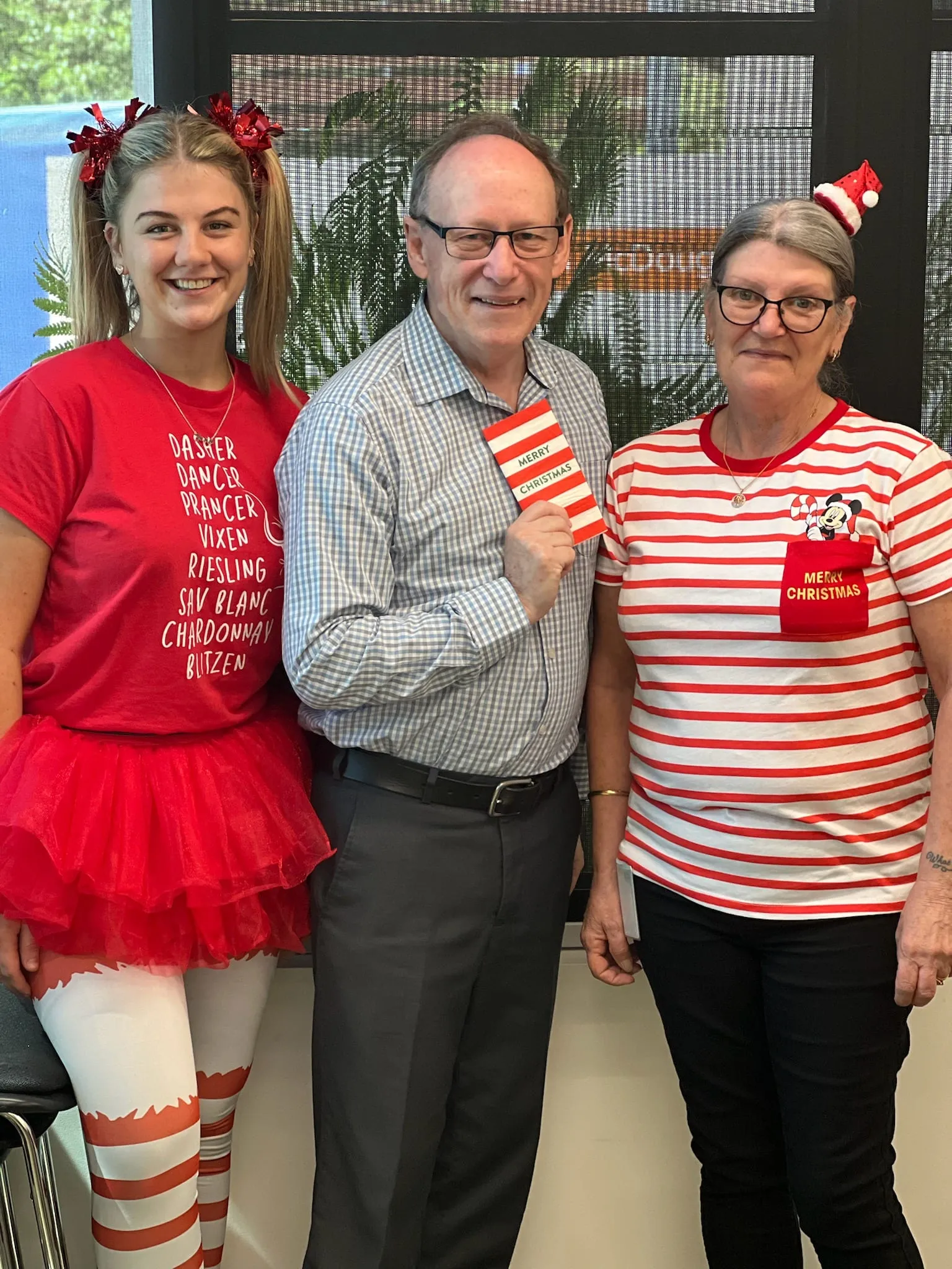 Three Myhorizon staff in Christmas dress-ups, the man in the middle holding a Merry Christmas card.