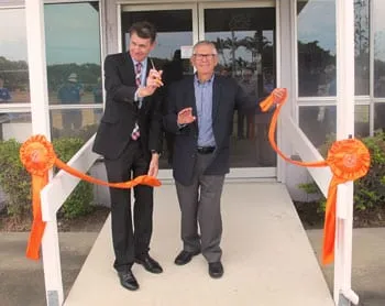 Two men cutting an orange ribbon across the entrance of the new Wynnum Lifestyle Centre, with orange rosettes on the doorposts.