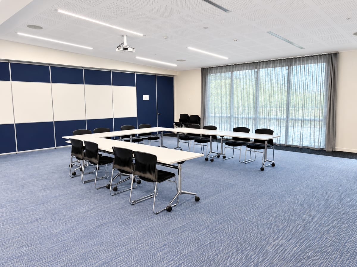 The Rosella Room with tables set in a U-shape, and a navy folding wall with whiteboards
