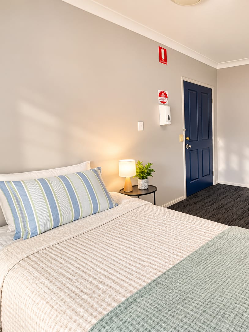 A made bed with a striped pillow in a bedroom at our Alexandra Hills short stay house.